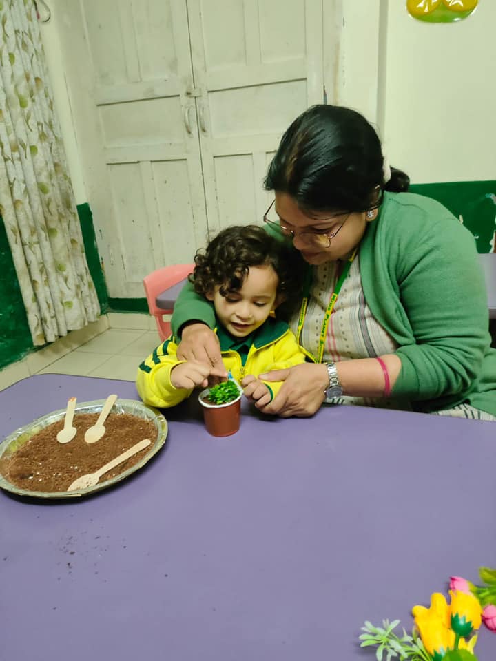 Teacher helping a toddler plant a seedling — nurturing hands-on learning