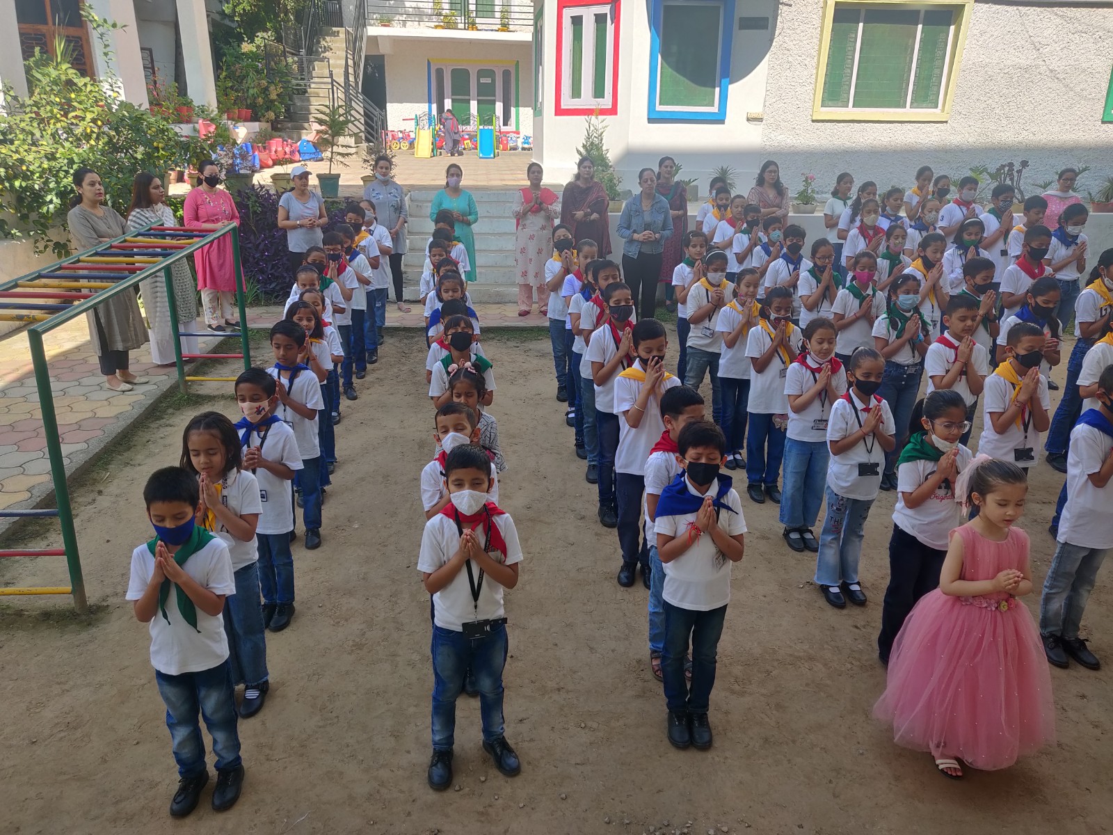 Morning prayer assembly with the entire school — colorful building in background