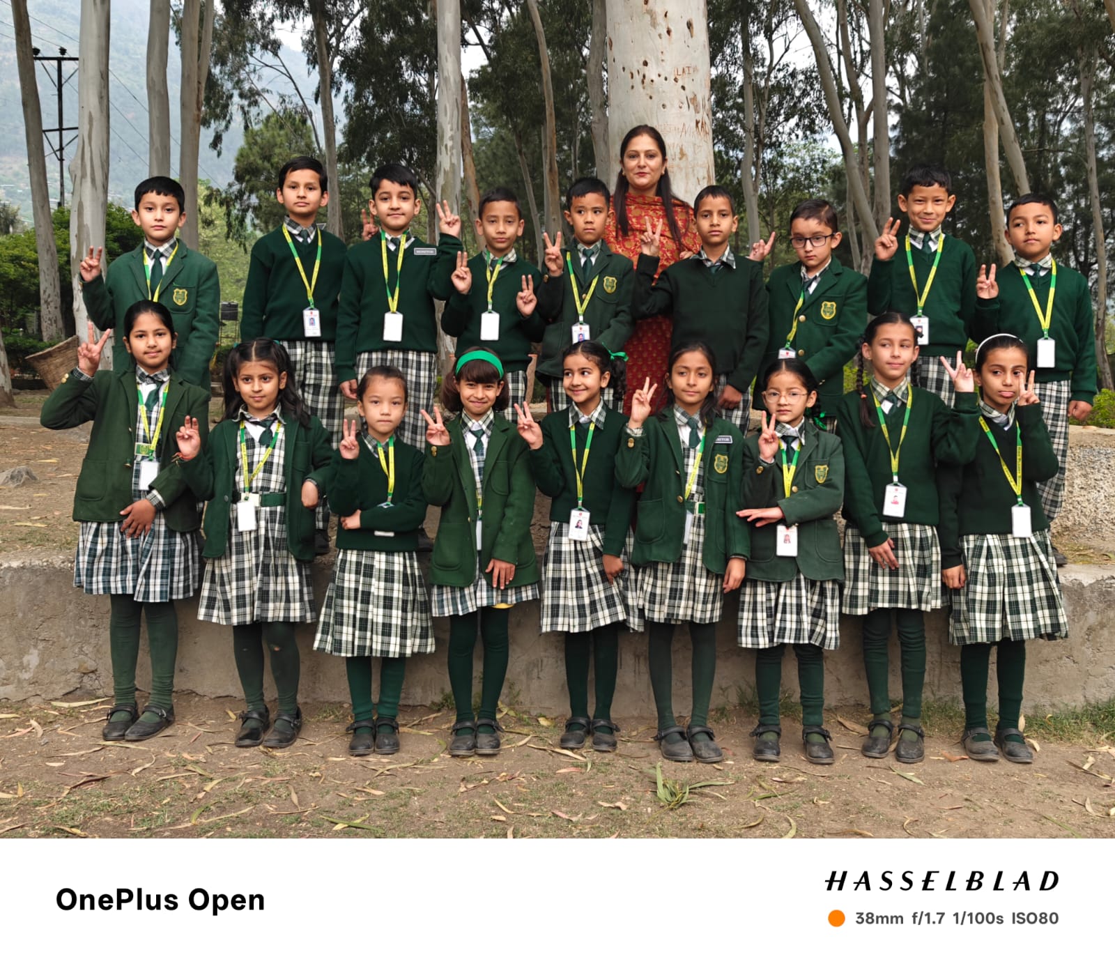 Class 2 group photo — students in green uniforms posing with teacher under eucalyptus trees