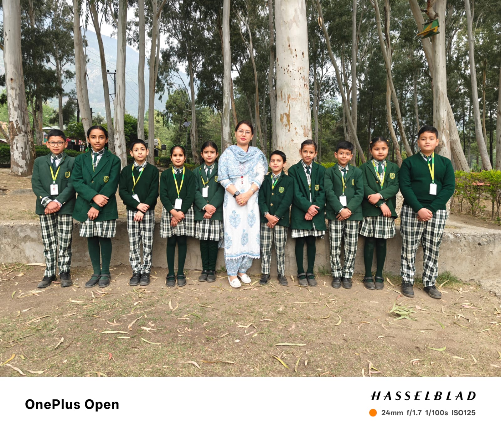 Class 5 group photo — students in green uniforms with Mrs. Pragya Sharma