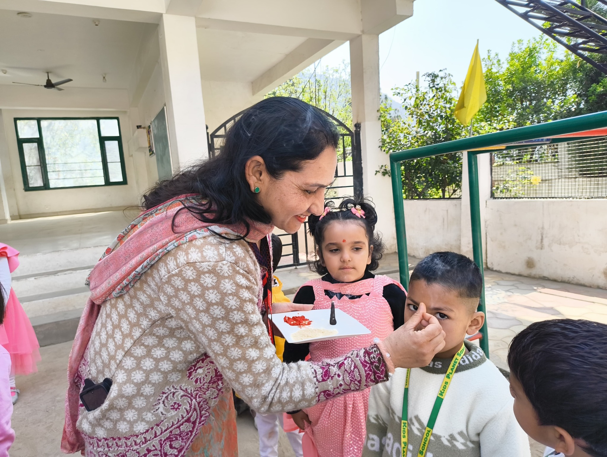 Teacher caring for a child at the school entrance — warmth and love