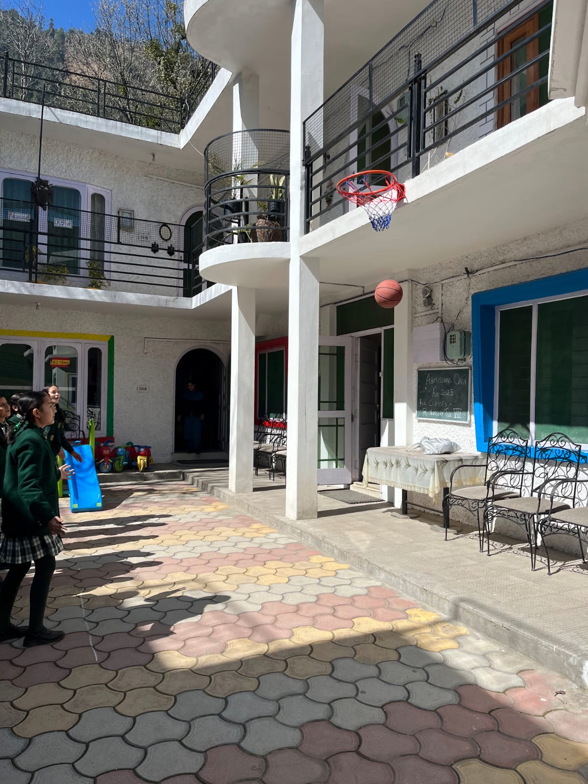 Students playing basketball in the school courtyard with mountain backdrop
