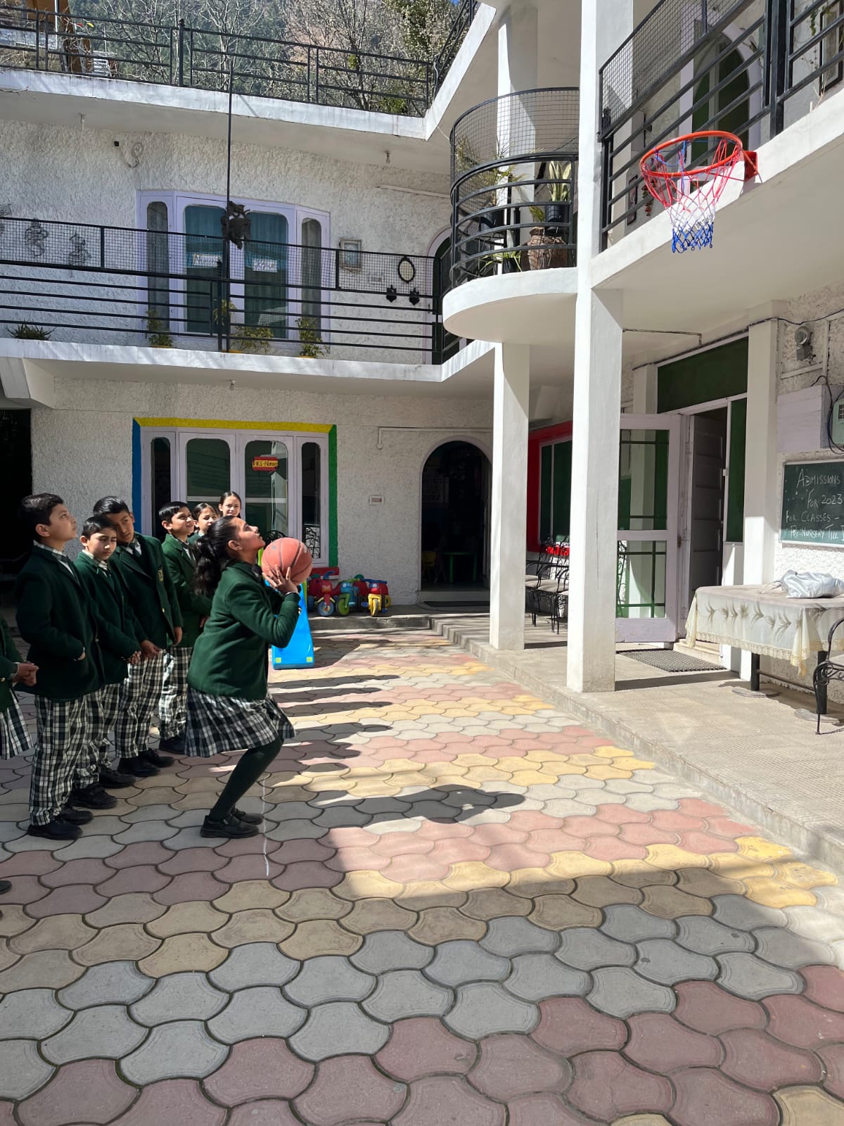 Student shooting basketball at the courtyard hoop — sports at Kids Planet