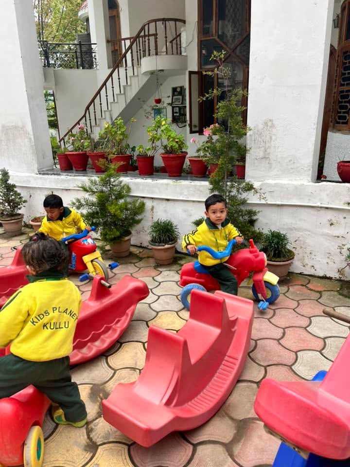 Toddlers riding colorful rocking horses in the school play area