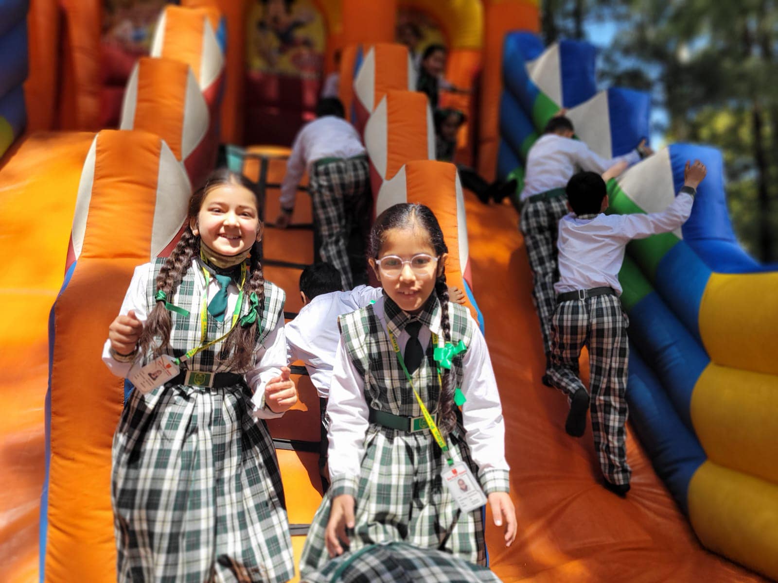 Pure joy — students laughing on a giant inflatable slide during a picnic